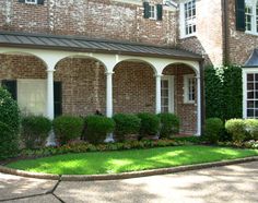 a brick house with green grass and flowers in the front yard