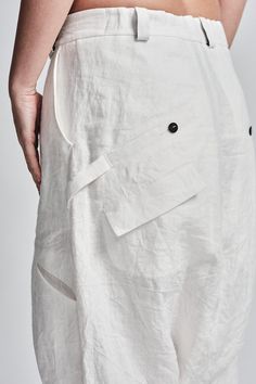 "Off-White Drop Crotch Boiled Linen Trousers with Buttons__ // EXPRESS DELIVERY ONLY __Semi Visible Front Closure with Black Buttons __3 Front & 2 Back Pockets __Fully Completed Bound Seams __Elastic Backside Waistband model__ bust 92 (36\"), waist 72 (28\"), hips 102 (40\"), biceps 28 (11''), height 177 (5'8\"), kg 65 (143 lbs) model wears size M | color: off-white fabric__ 100 linen care__ dry cleaning do not bleach do not tumble dry do not iron to keep wrinkle effect sizing__ size XS (US White Straight Pants With Buttons, White Bottoms With Side Pockets For Work, White Bottoms With Buttons And Relaxed Fit, White Linen Bottoms With Button Closure, White Trousers With Buttons, Low Crotch Pants, Off White Pants, Winter Trousers, Linen Coat