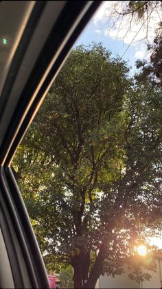 the sun shines through the trees in front of a car's side view mirror