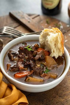 a bowl of beef stew with bread on the side