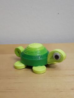 a green turtle toy sitting on top of a wooden table