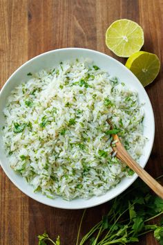 a white bowl filled with rice and garnished with cilantro on a wooden table