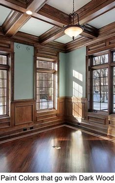 an empty room with wood paneling and windows on the walls, along with hardwood flooring