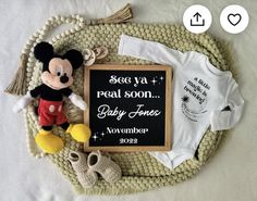 there is a baby announcement with a mickey mouse and other items on the mat next to it