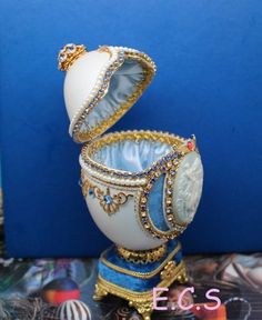 an egg is sitting on top of a stand with its lid open and jewelry around it