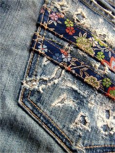 the back pocket of an old pair of jeans with flowers on it and torn edges