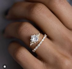 a woman's hand with two engagement rings on it