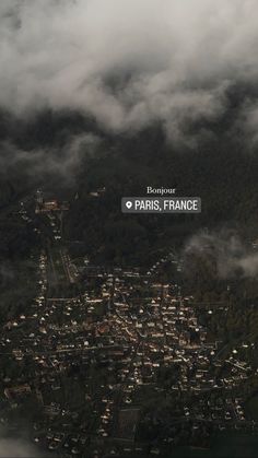 an aerial view of a city surrounded by mountains and clouds with the words paris, france above it