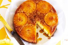 a pineapple upside down cake on a white plate with a yellow flowered tablecloth