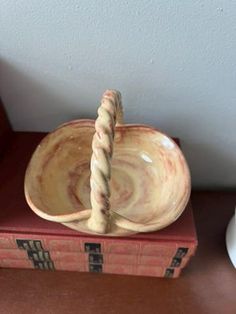 a small bowl sitting on top of a stack of books with a rope sticking out of it