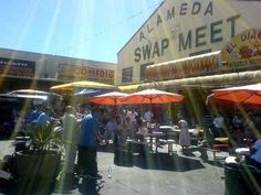 many people are sitting at tables under umbrellas in front of a building with a sign on it