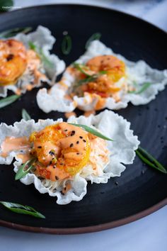 three small appetizers are sitting on a black plate