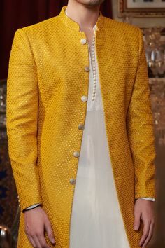 Mustard sherwani with thread embroidery and sequin work. Comes with raw silk straight pants.
Component: 2
Pattern: Embroidery
Type Of Work: Thread and Sequin
Neckline: Band
Sleeve Type: Full
Fabric: Georgette and Raw Silk
Color: Yellow
Other Details: 
Closure: Button front
Note: Inner kurta worn by the model is not for sale
Occasion: Wedding - Aza Fashions Sawan Gandhi, Raw Silk Embroidery, Embroidered Sherwani, Haldi Outfit, Pattern Embroidery, Thread Embroidery, Silk Embroidery, Pant Set, Raw Silk