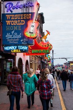 three women walking down the street in front of a bar and restaurant with neon signs