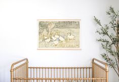 a baby crib in front of a painting on the wall next to a potted plant