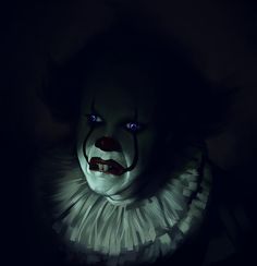 a creepy clown in the dark with blue eyes