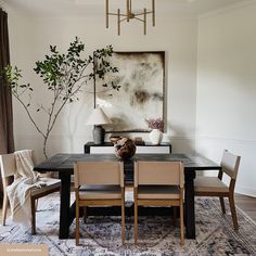 a dining room table with chairs and a painting on the wall in the back ground