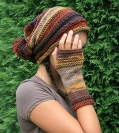 a woman wearing a knitted hat and mitten covers her face with both hands