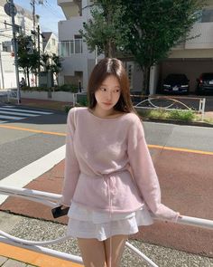 a young woman standing on the side of a road