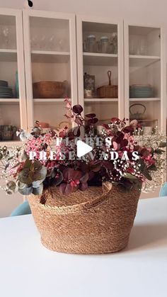 a basket filled with lots of flowers on top of a white table next to shelves