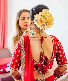 the back of a woman's red saree with flowers in her hair and jewelry