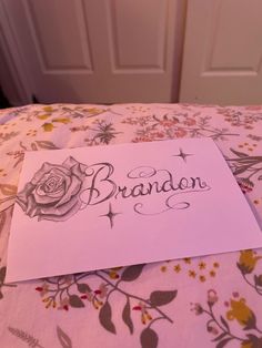 a note that is laying on top of a bed with a flower pattern and the word brandon written in cursive writing