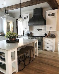 a kitchen with white cabinets and an island in the middle, surrounded by stools