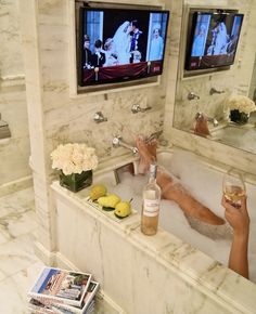 the woman is relaxing in the bathtub with her feet up on the tub and holding a glass of wine