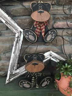 two wooden teddy bears sitting next to each other on a shelf near a potted plant