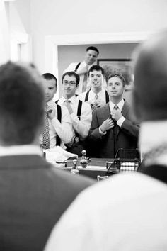 a group of men standing next to each other in front of a man wearing a suit and tie