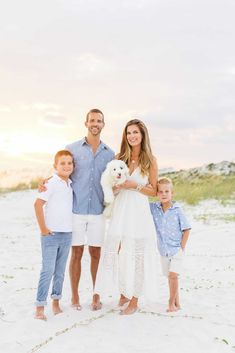 a family posing for a photo on the beach with their dog and two children in front of them