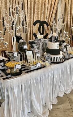 a table topped with black and white desserts next to a drapes covered wall