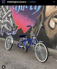 a blue bicycle parked in front of a wall with graffiti on it's side