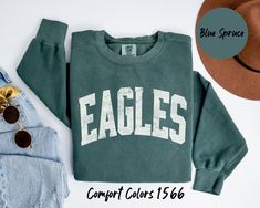 "\"Unleash the Spirit with Our Custom Eagles Mascot Comfort Colors Sweatshirt.\" This sweatshirt brings school pride and team spirit to a whole new level. With our custom mascot design, you can proudly represent your school or organization wherever you go. Made with the finest Comfort Colors fabric, it offers unparalleled comfort and durability. Whether you're cheering from the stands, on the field, or simply hanging out with friends, this sweatshirt is your ultimate go-to for coziness and style Cheap Tops For School Events With School Spirit, School Spirit Apparel, School Staff Tshirt Ideas, Casual School Tops For Sports Season, Casual Tops For School Sports Season, Soccer Spirit Wear, Casual Tops For School Football Season, Casual School T-shirt For Football Season, Casual School Sweatshirt With Team Name