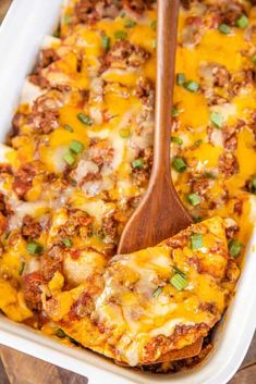 beef and cheese enchilada casserole in a white dish with a wooden spoon