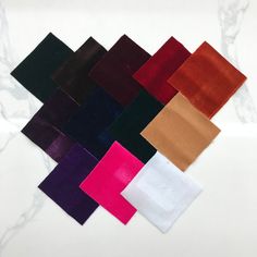 several different colors of cloth on a white table with marbled surface in the background