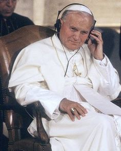 a man sitting in a chair while talking on a cell phone and wearing headphones