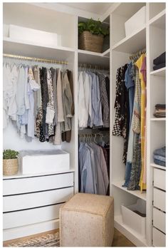 an organized closet with clothes hanging on the shelves and a footstool next to it