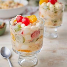 two desserts with fruit in them on a table next to other dishes and spoons