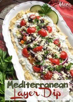 a white platter filled with salad and vegetables on top of a red table cloth