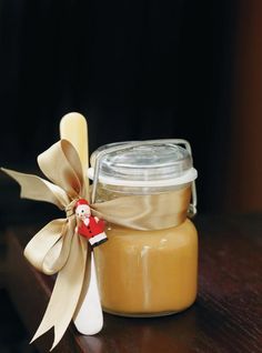 a glass jar filled with liquid sitting on top of a wooden table next to a spoon