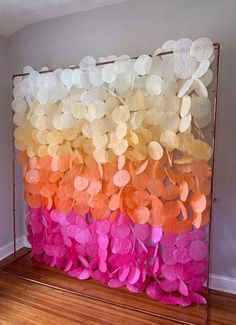 an art piece made out of paper flowers on a wooden floor in front of a wall