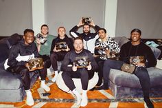 a group of men sitting on top of couches holding remotes in their hands