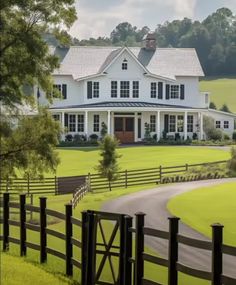 a large white house sitting on top of a lush green field next to a road