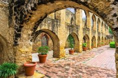 an old brick building with arches and potted plants