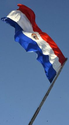 an image of a flag flying in the air with blue sky behind it and red white and blue