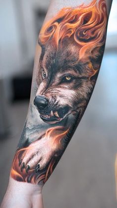 a man's arm with a wolf and flames tattoo on his arm, which is covered in fire