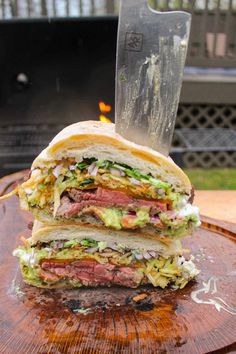 a cut in half sandwich sitting on top of a wooden table next to a knife