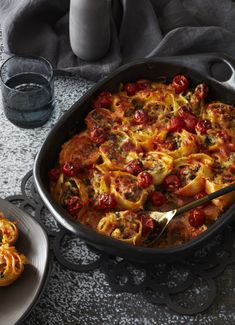 a casserole dish with tomatoes and cheese in it on a table next to other dishes