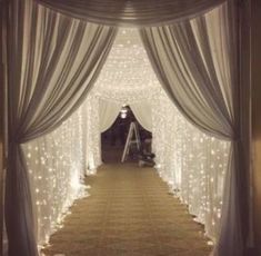 an aisle decorated with white lights and drapes